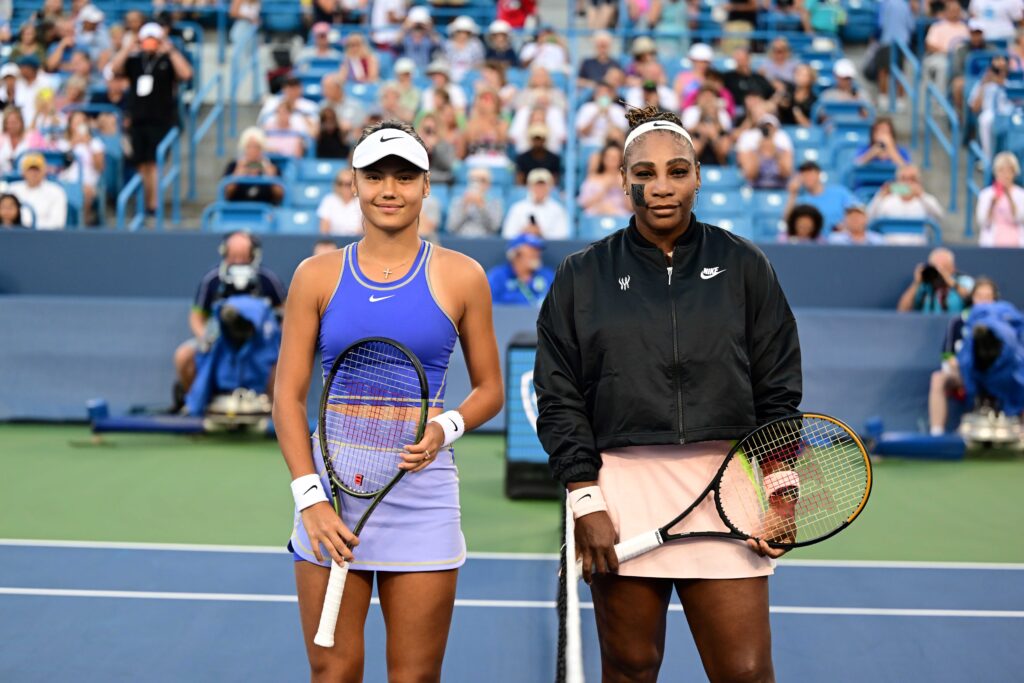 Emma Raducanu and Serena Williams smiling together at the net