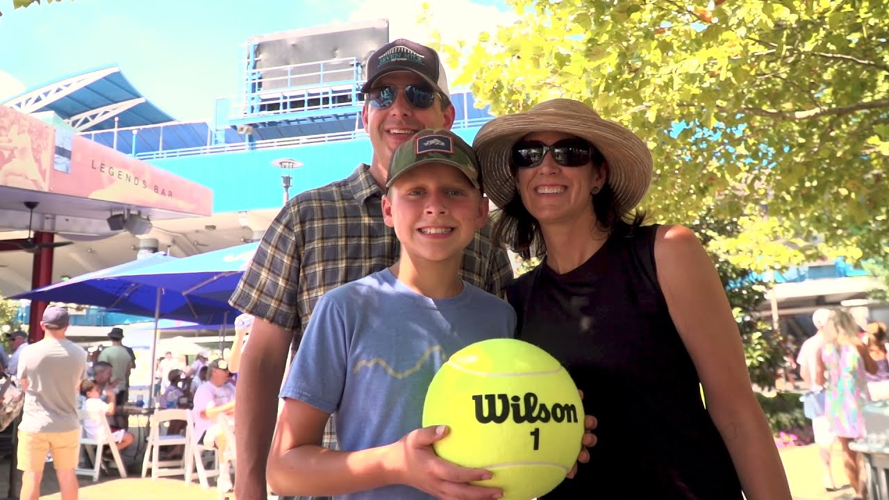 family posing with giant tennis ball outside of stadium