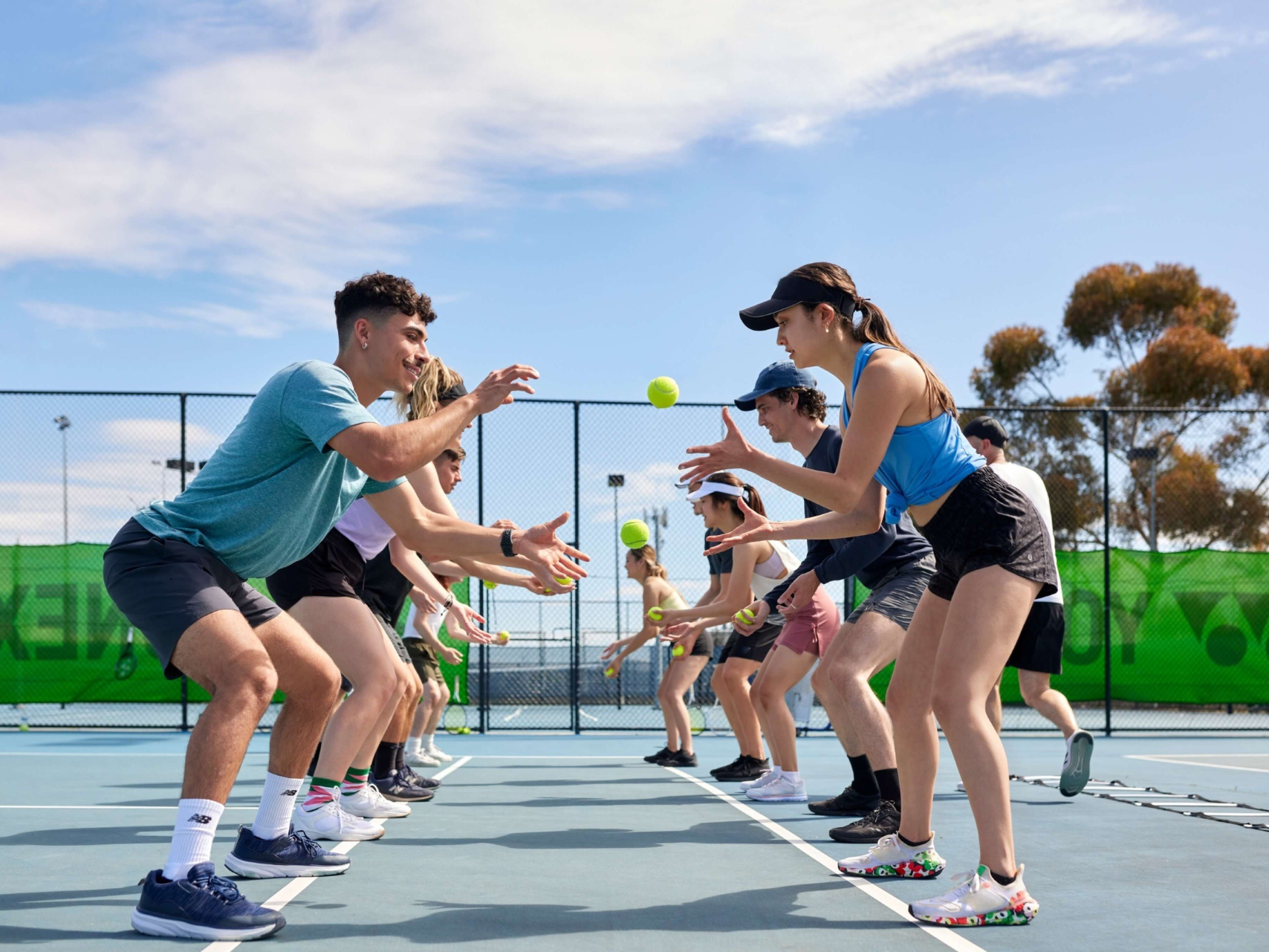 Young adults toss tennis balls