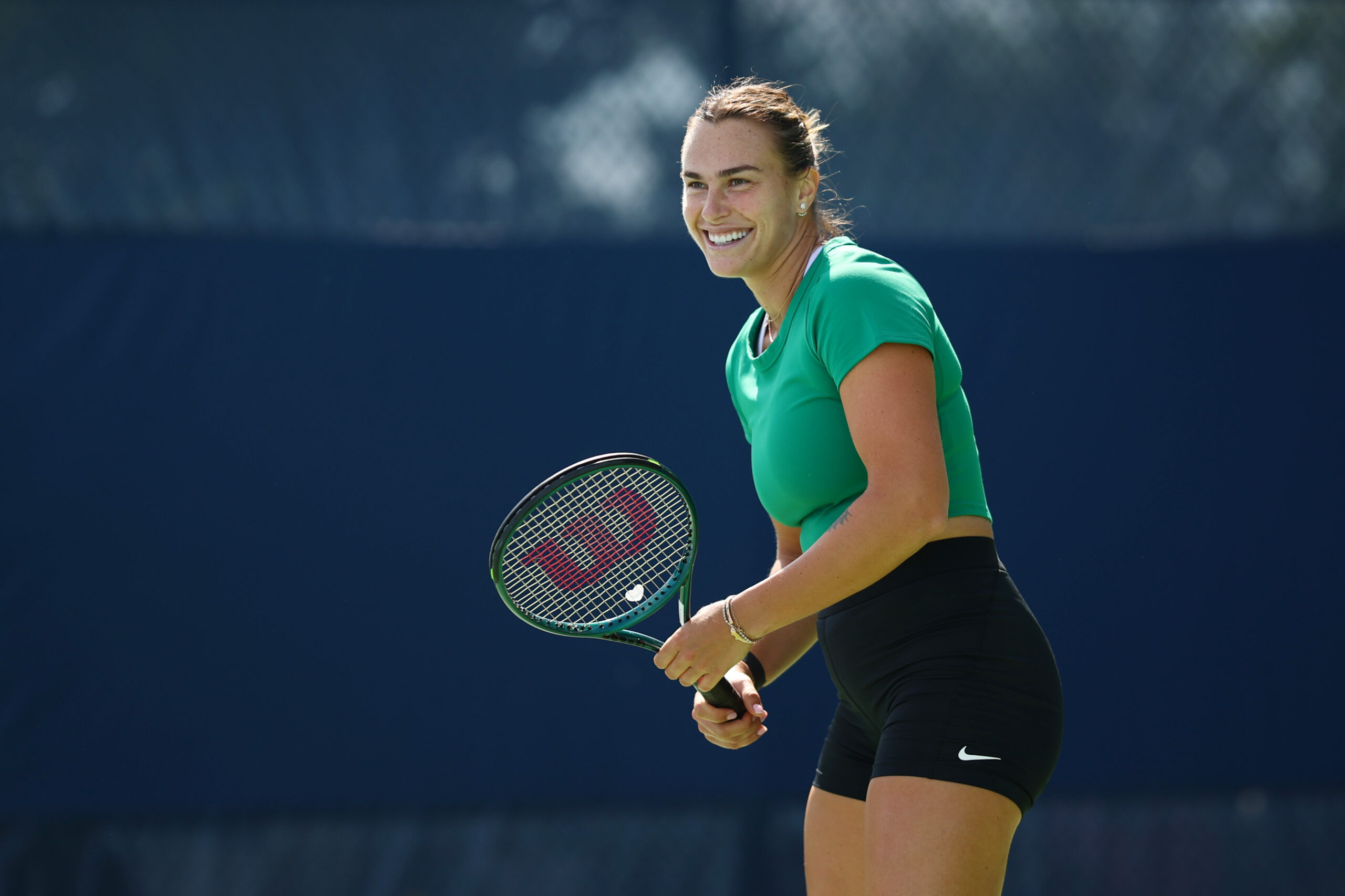 Aryna Sabalenk smiling with a tennis racket.