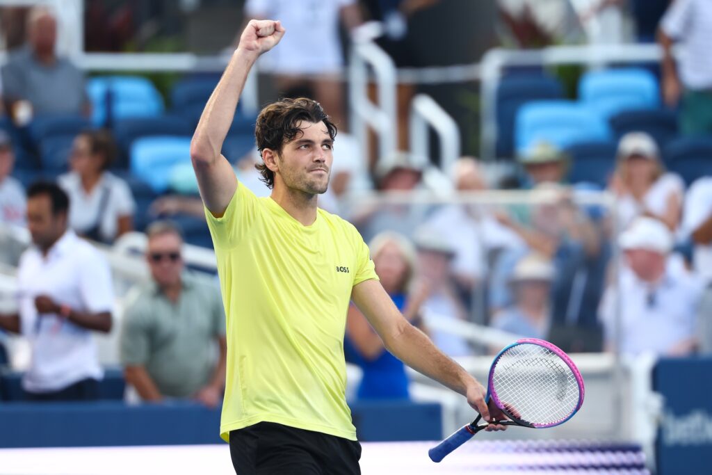 tennis player raising hand to acknowledge crowd