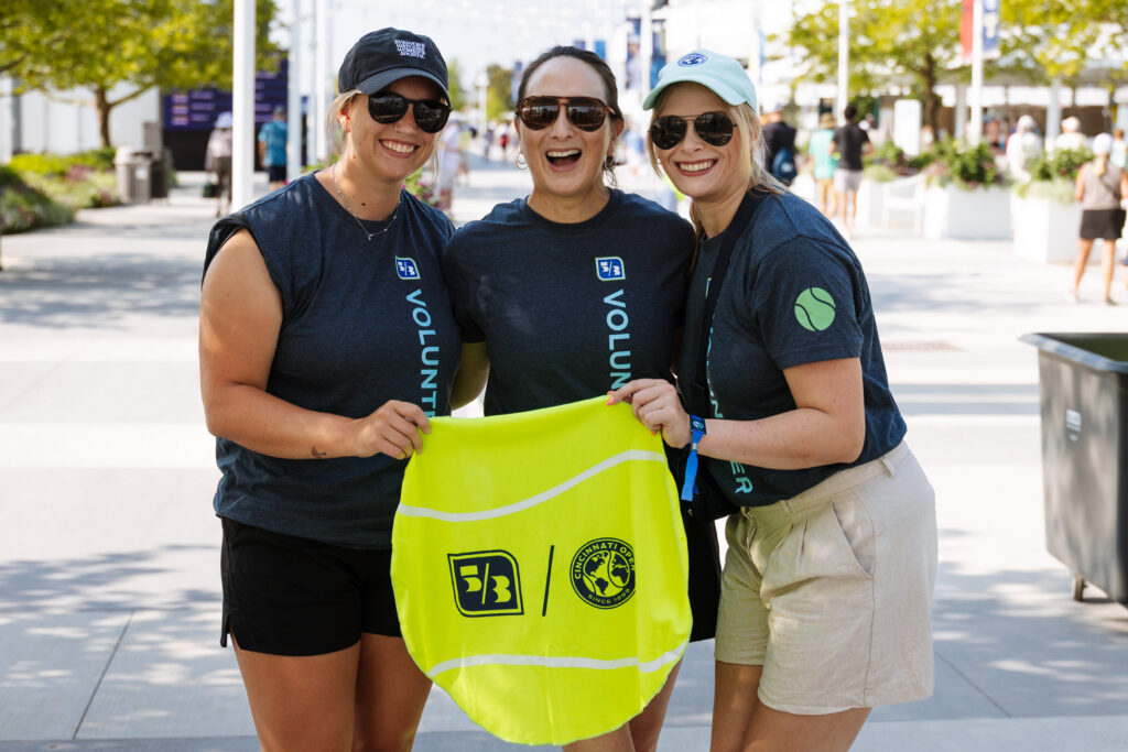 three women hold up a neon green bag