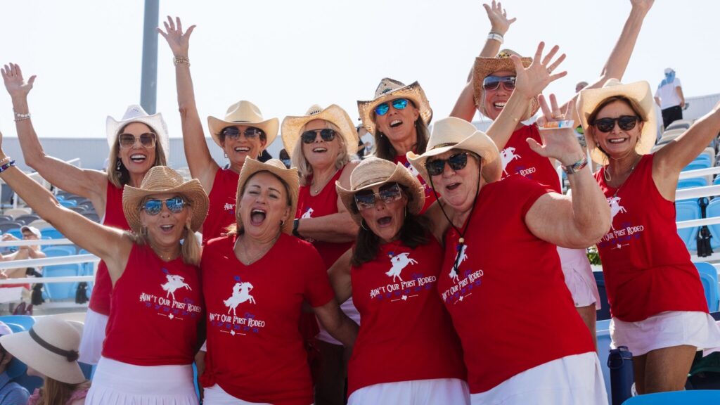 Group of women raising their hands and smiling at the camera