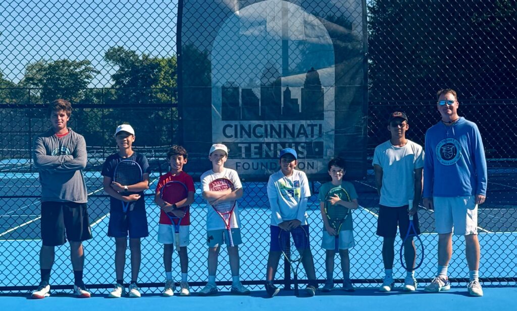 A group poses in front of a sign that reads 'Cincinnati Tennis Foundation'