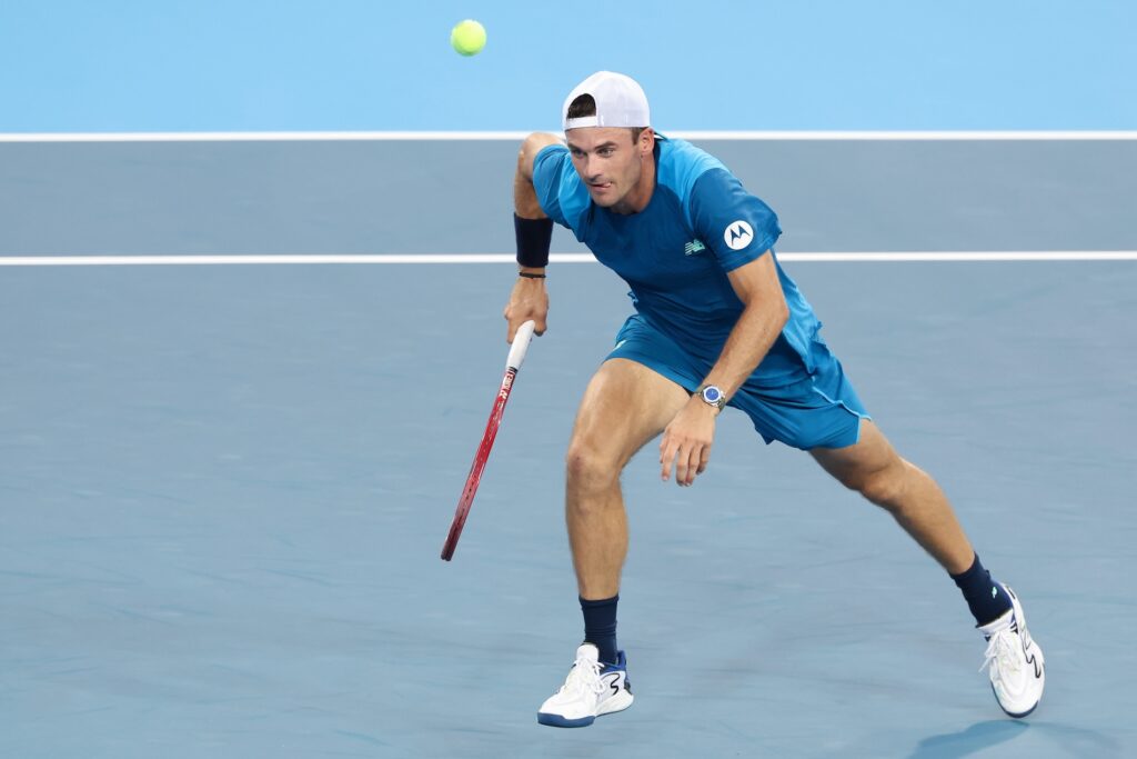 ATP player on court rushing to hit the ball