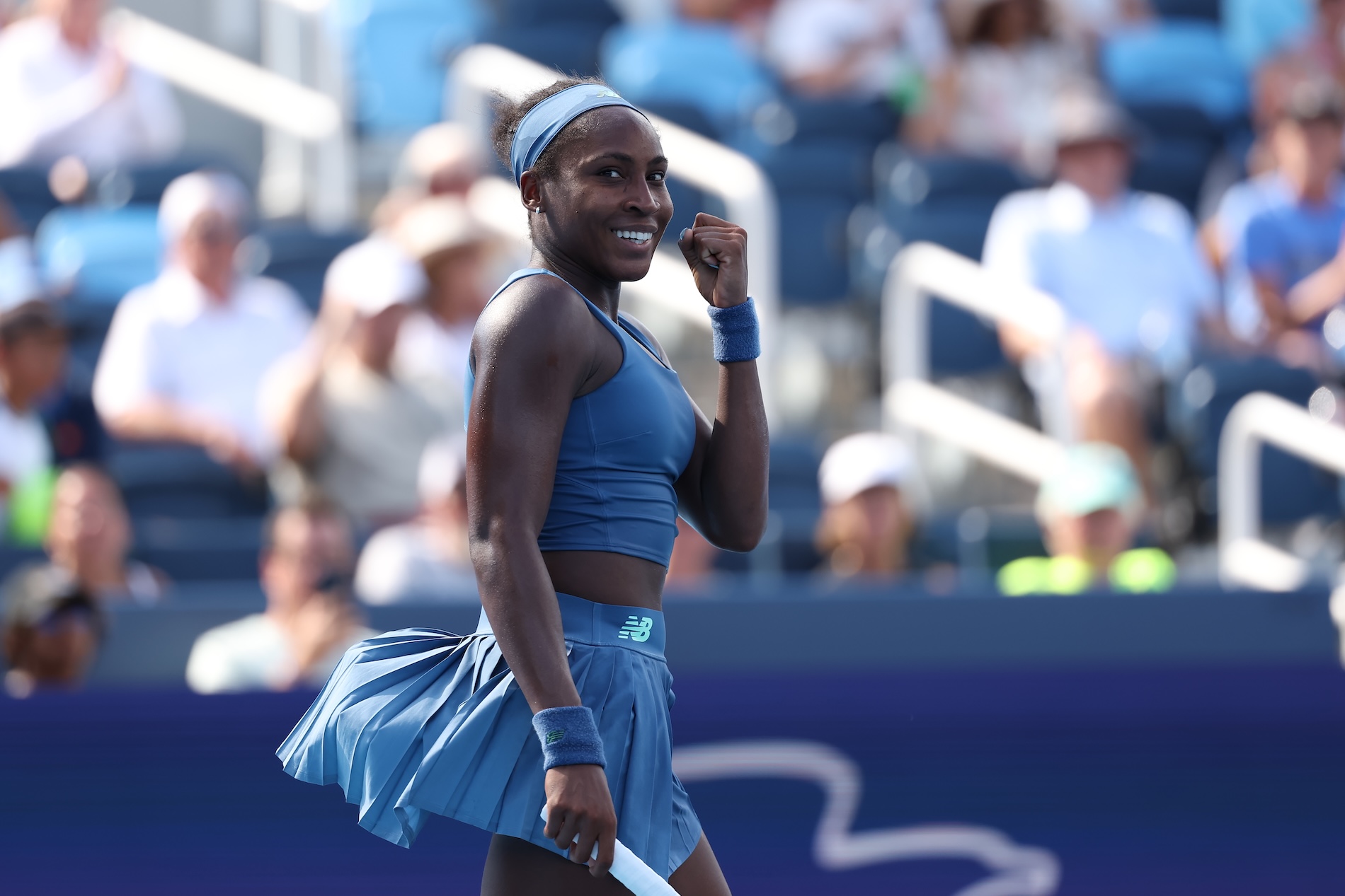 WTA player smiling on court with her fist up in celebration