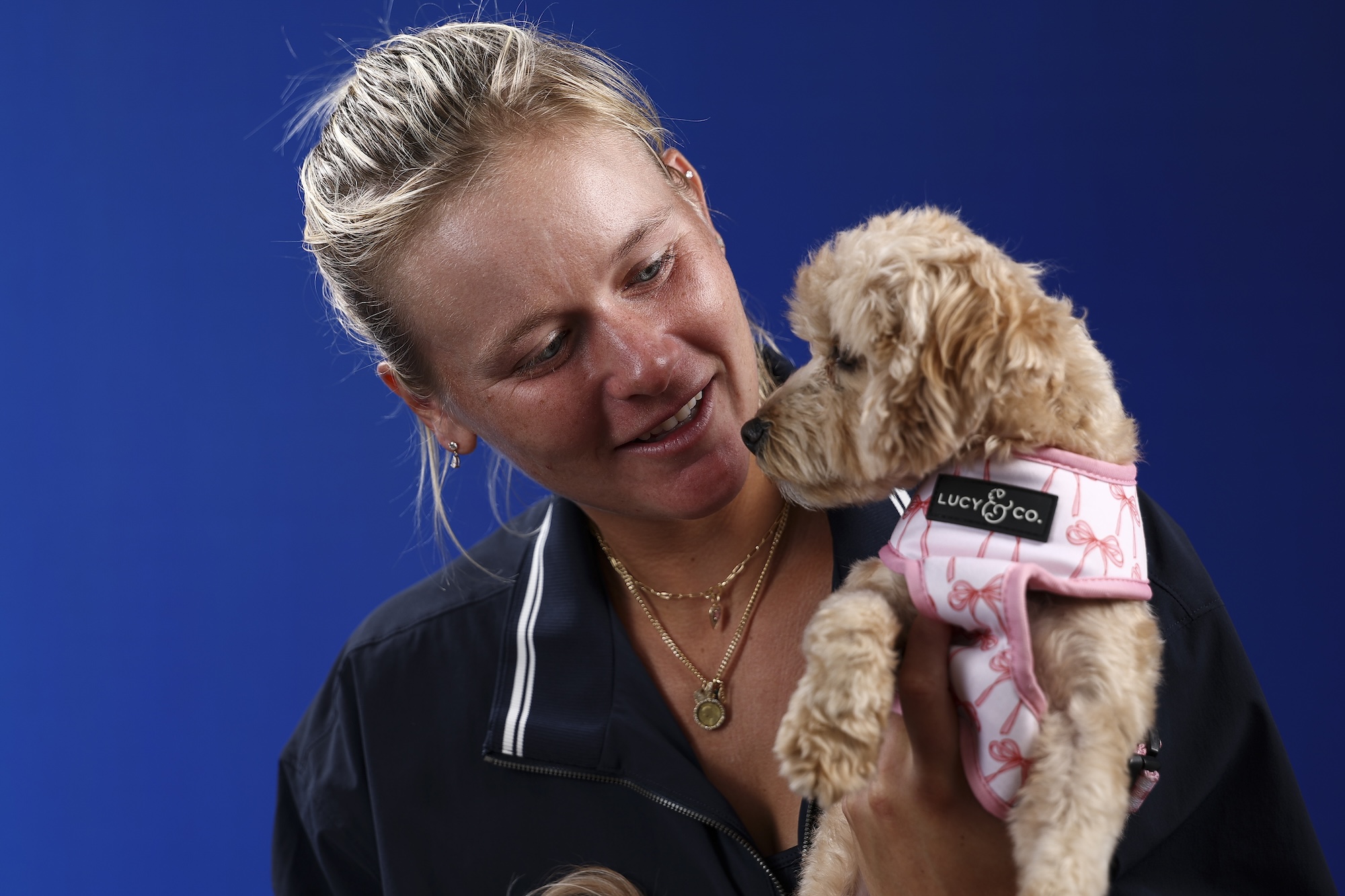 Peyton Stearns holds a maltipoo dog in a pink harness