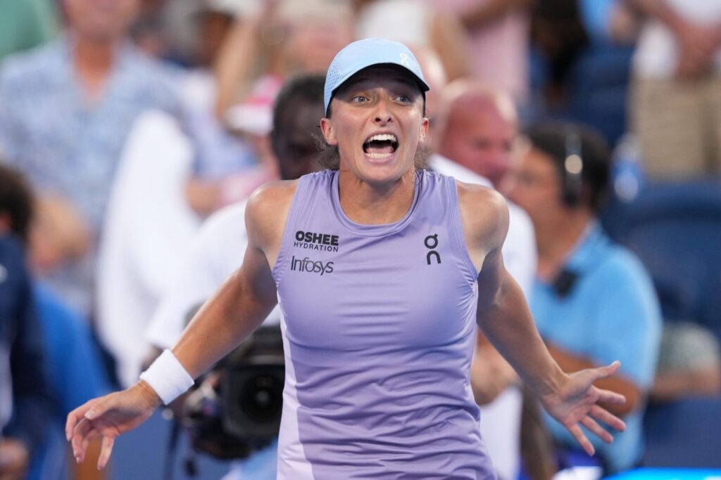 Pegula in a purple sleeveless top and blue cap appears to be shouting or expressing intense emotion during a tennis match.