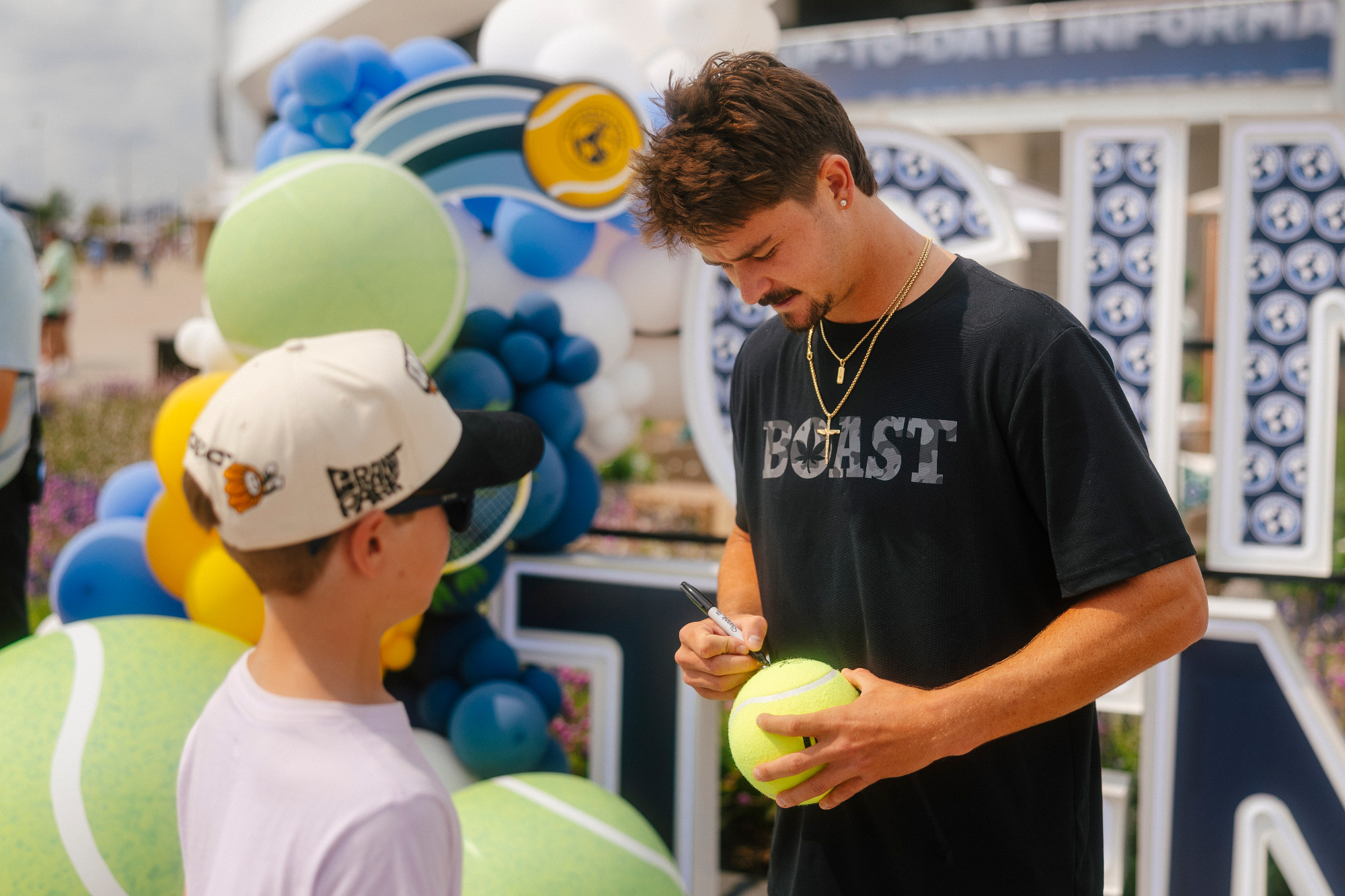 J.J. Wolf signs a tennis ball for a fan