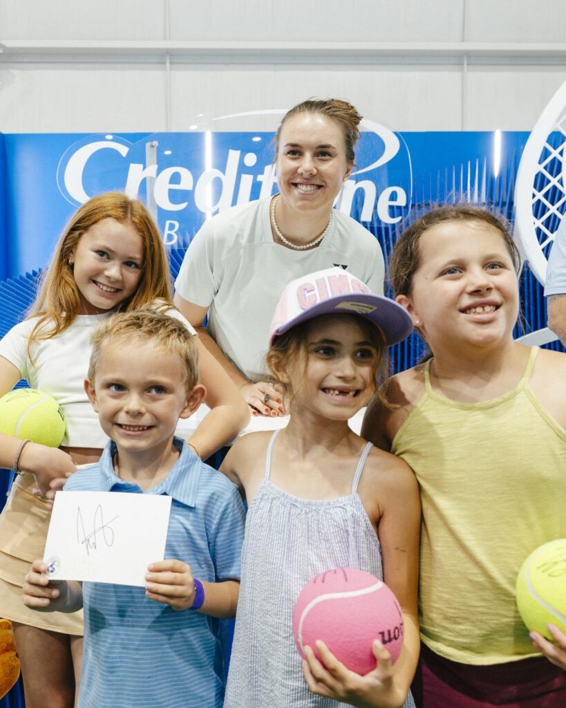 Linda Noskova smiles behind a group of four children holding tennis balls and a signed card at the 2026 Cincinnati Open.