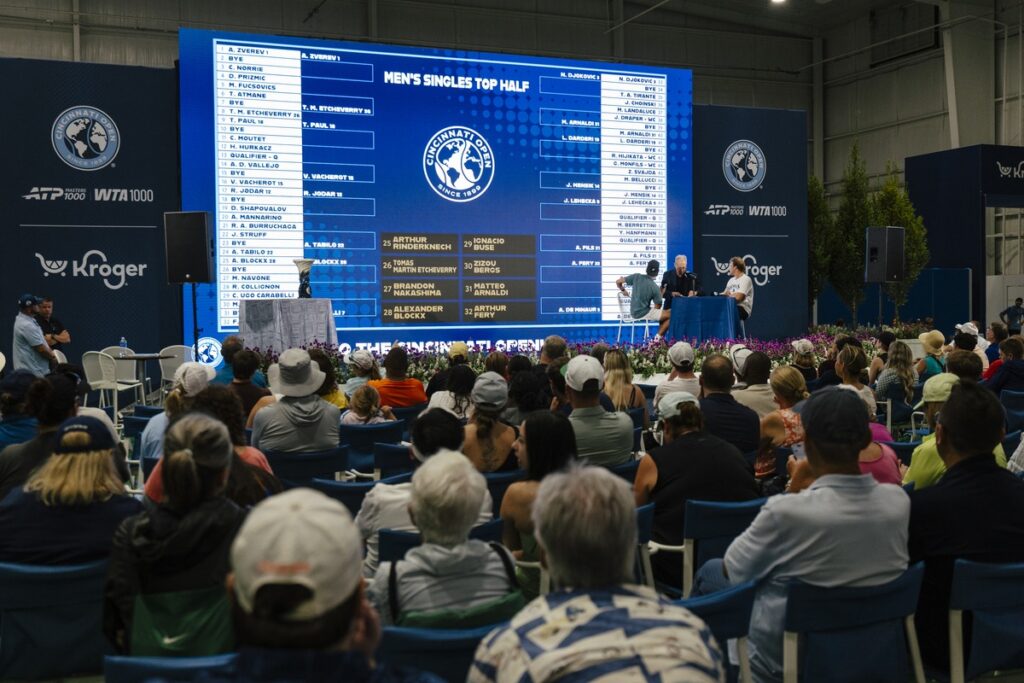 a croud watching a mens singles draw announcement on stage